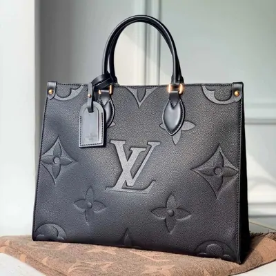 Black leather tote with embossed monogram pattern and a small hang tag