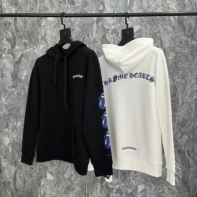 Black and cream hoodies hanging side by side on a rail against a grey wall
