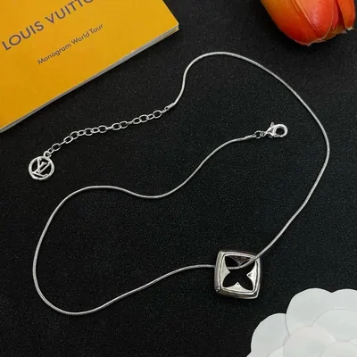 Thin silver necklace with a small black square pendant on a white tray